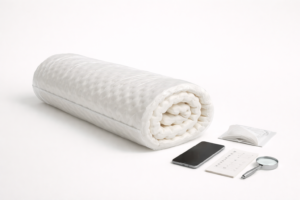 Rolled foam mattress topper with a phone and checklist showing donation rules vary.